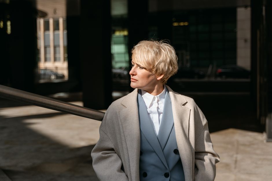 Woman walking confidently in a city street, wearing a stylish and professional outfit made from sustainable fabrics, showcasing workwear options.