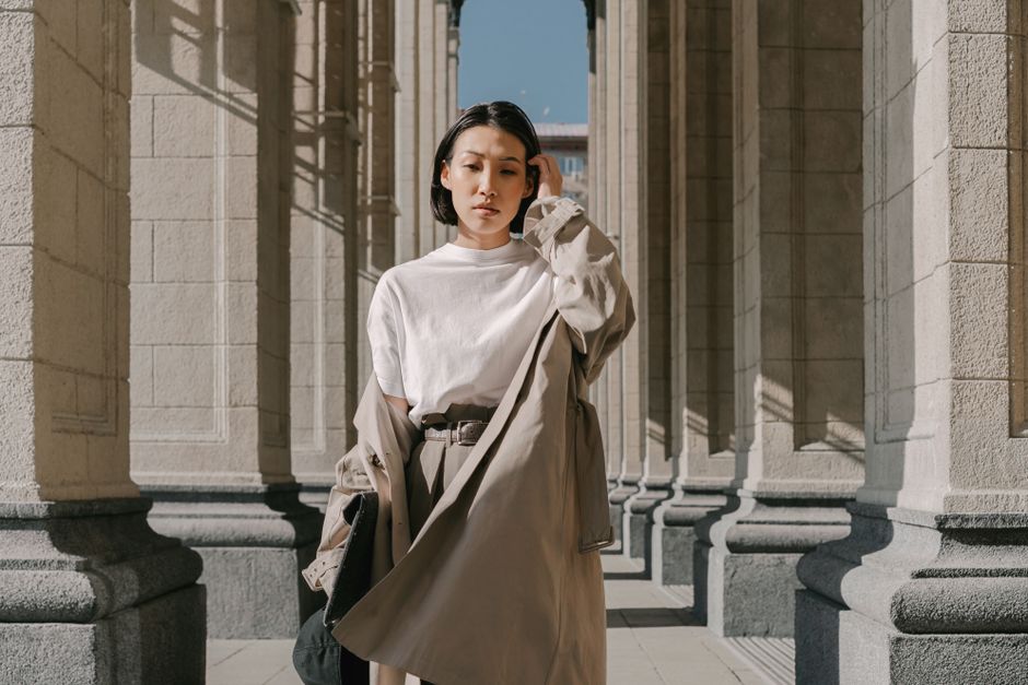 A woman dressed in a chic, neutral-toned workwear outfit, including a tailored blazer and trousers, confidently walking through a European city street, embodying capsule style.