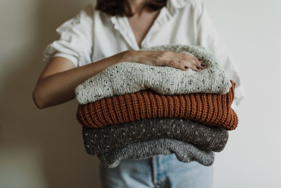 Close-up of a woman's torso, demonstrating different thermal and mid-layers, like a merino wool base layer and a cashmere sweater, ready for cold weather.