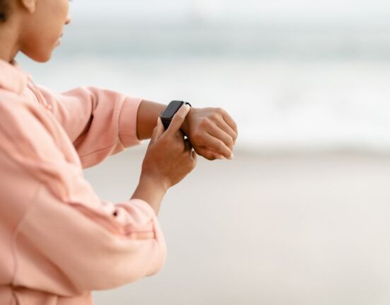 A woman examining the veins on her wrist to determine her skin undertone, with a focus on natural light.