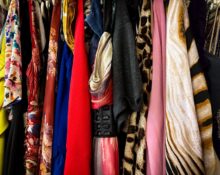A woman selecting items from a well-organized capsule wardrobe, featuring neutral colors and classic pieces.