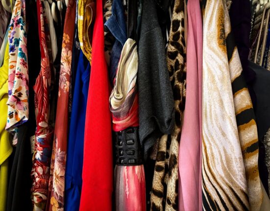 A woman selecting items from a well-organized capsule wardrobe, featuring neutral colors and classic pieces.
