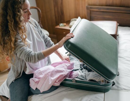 Woman thoughtfully packing a neatly organized suitcase with versatile clothing for a European trip.