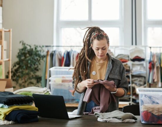Woman thoughtfully examining sustainable fabrics on a clothing rack, representing mindful shopping for a sustainable wardrobe.