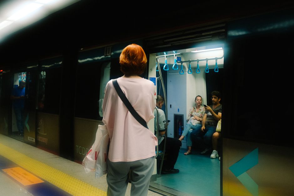 A woman on a crowded metro in a European city, securely holding an anti-theft crossbody bag close to her body, demonstrating ease of access and security.