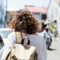 A woman confidently navigating a busy European city street with a stylish anti-theft backpack, illustrating comfortable and secure urban travel.