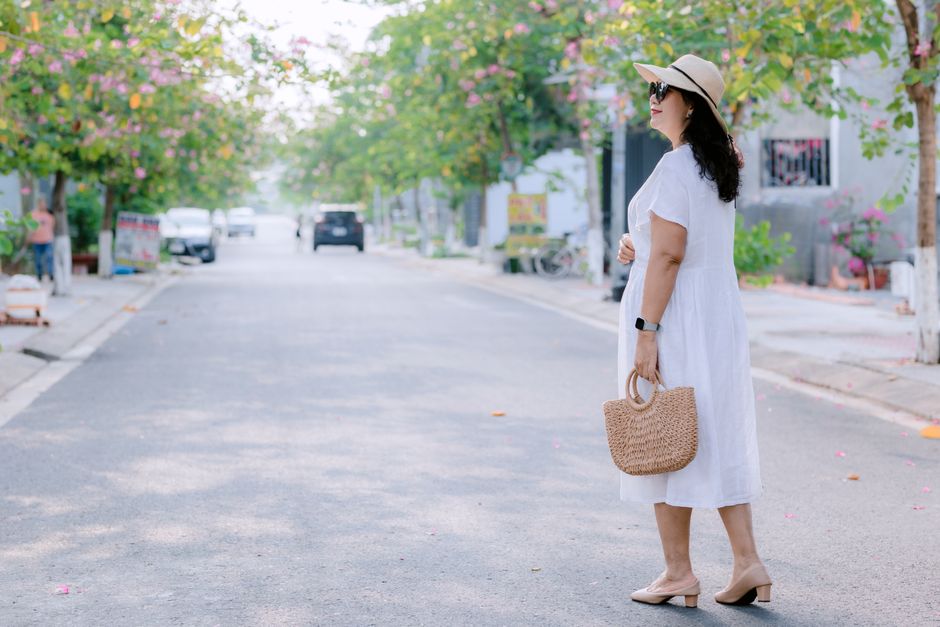 A woman wearing comfortable walking shoes, smiling as she strolls along a vibrant city street with diverse architecture in the background.