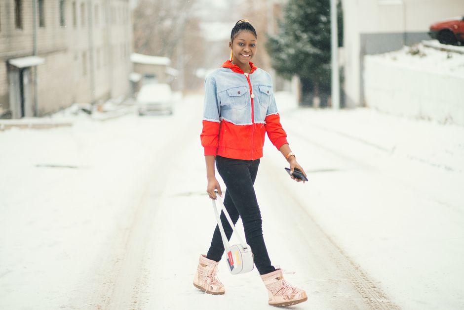 A woman in a warm, insulated parka, beanie, and waterproof boots navigating a snowy city street, illustrating practical women's winter outfits for extreme cold in urban settings.