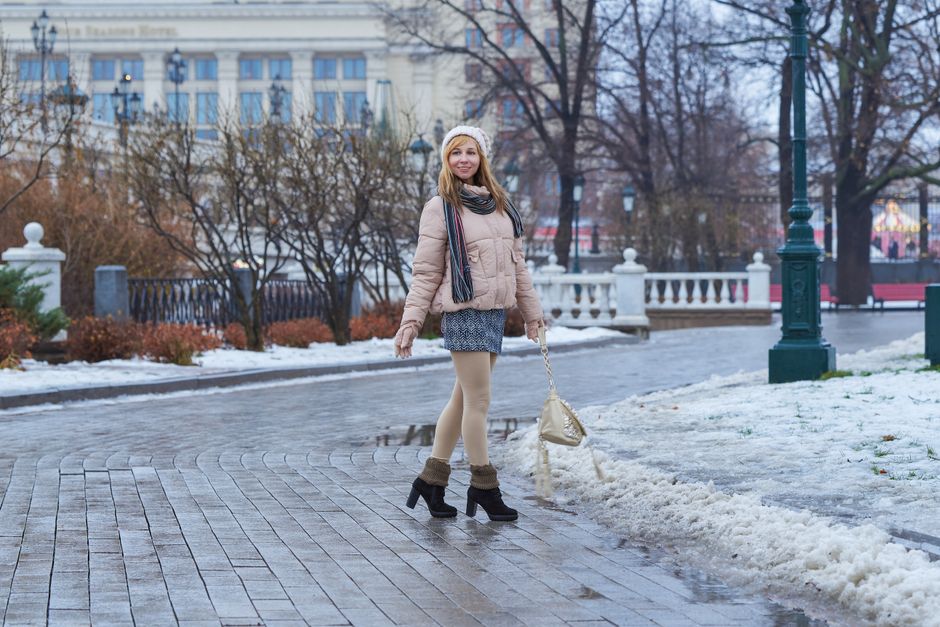 A woman in a stylish tailored wool coat, warm scarf, and waterproof boots, navigating a snowy pedestrian area in a European city, perhaps Berlin or Paris.