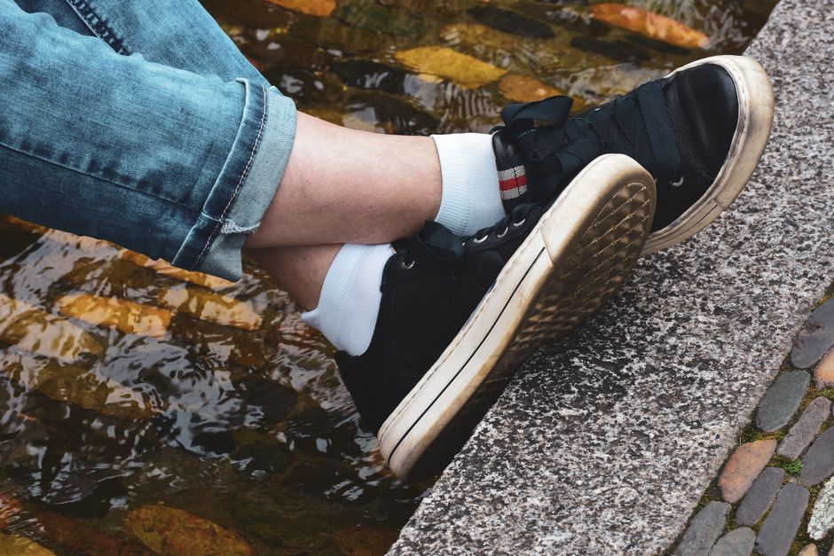 A woman wearing stylish, comfortable sneakers walking confidently on historic European cobblestones, showcasing ideal travel footwear.