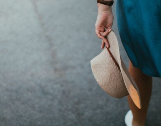 Woman in light linen trousers and a breezy cotton top walking in a European city.