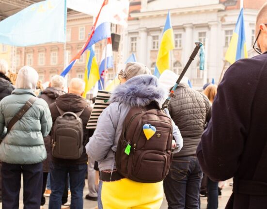 Woman wearing a modern anti-theft backpack confidently navigating a busy cobblestone street in a European city.