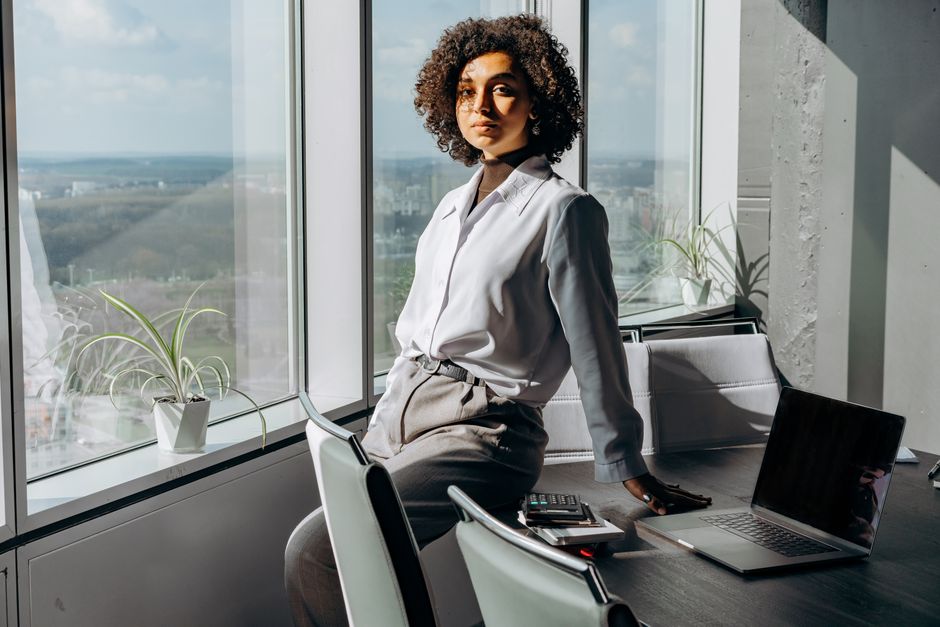 A professional woman stands in a modern office, wearing elegant wide-leg Tencel trousers and a light linen blouse, perfectly balancing workwear and comfort in humid conditions.